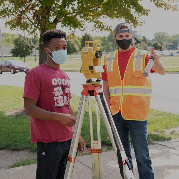 Two Field Engineering students use a sensor outdoors.